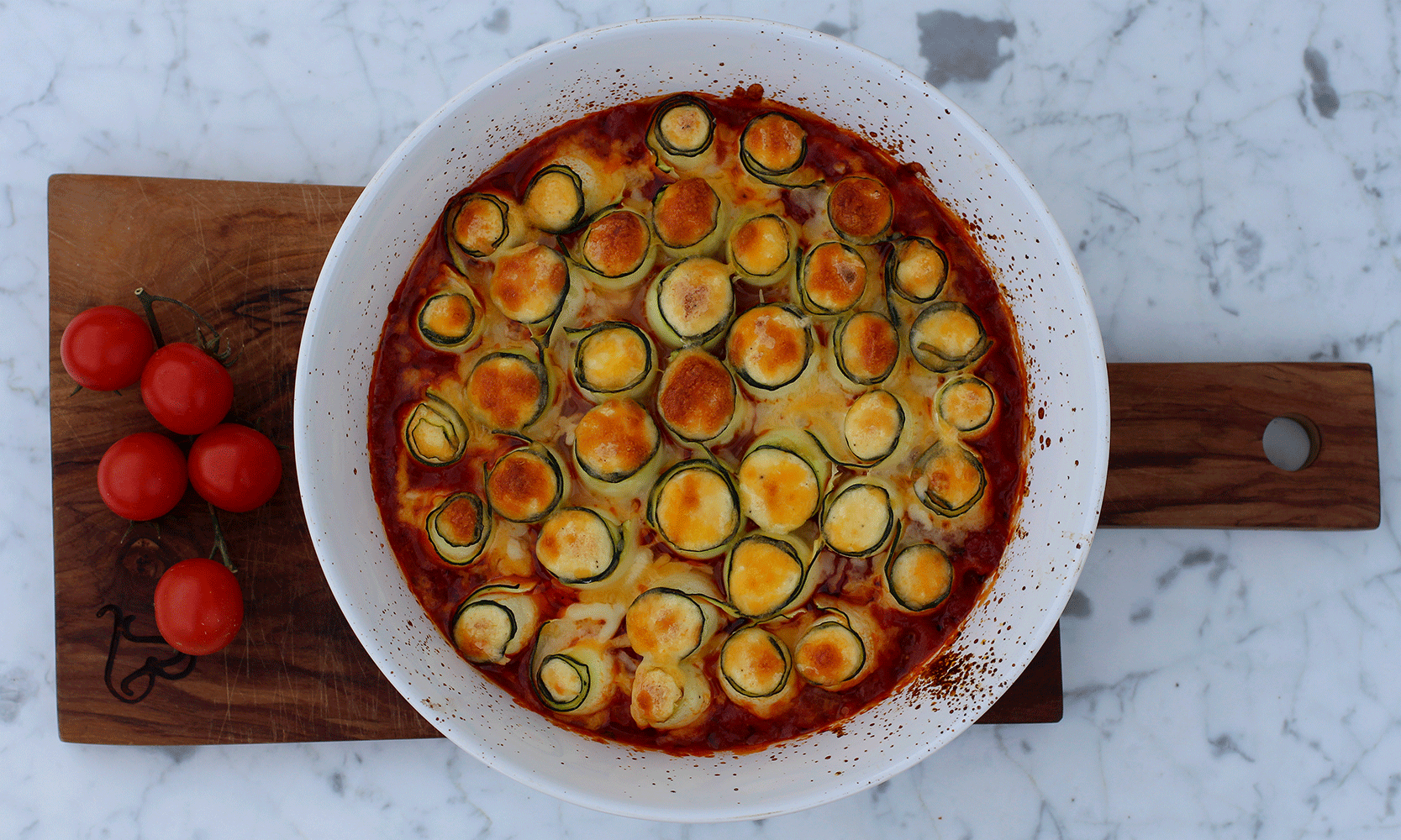 Squashruller med ricotta i tomatsaus i hvit form på treplate